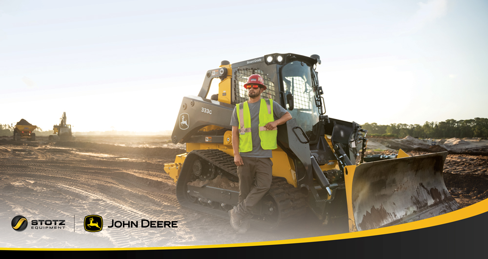 Image of man standing in front of John Deer 333g Skid Steer
